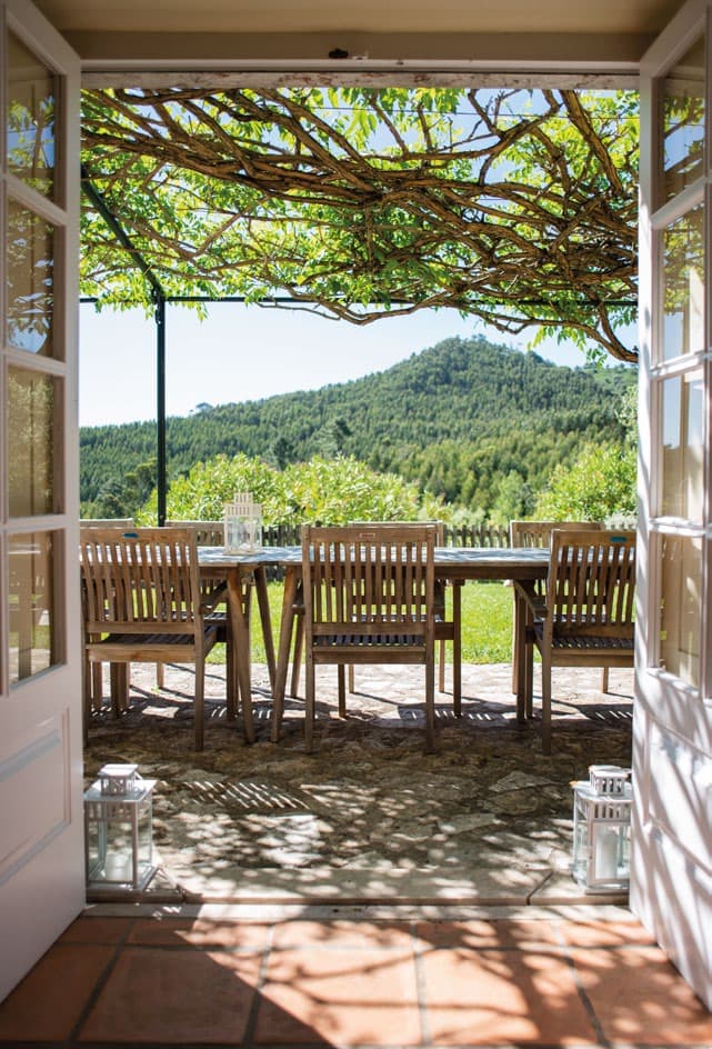 Through the open doors at Marreco House, a vine-covered terrace looks out over the wooded hills