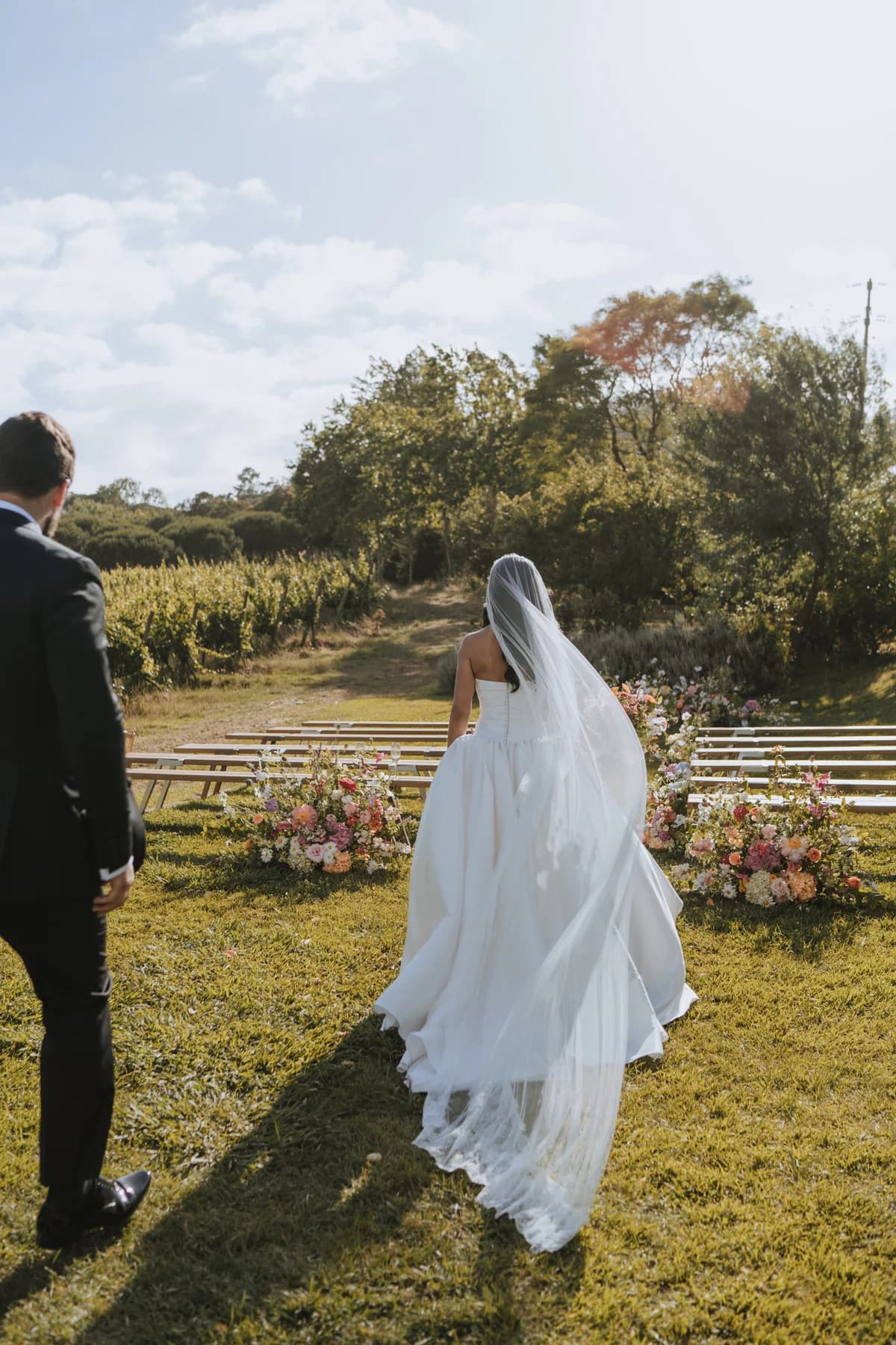 A bride approaching the outdoor ceremony across the lawn