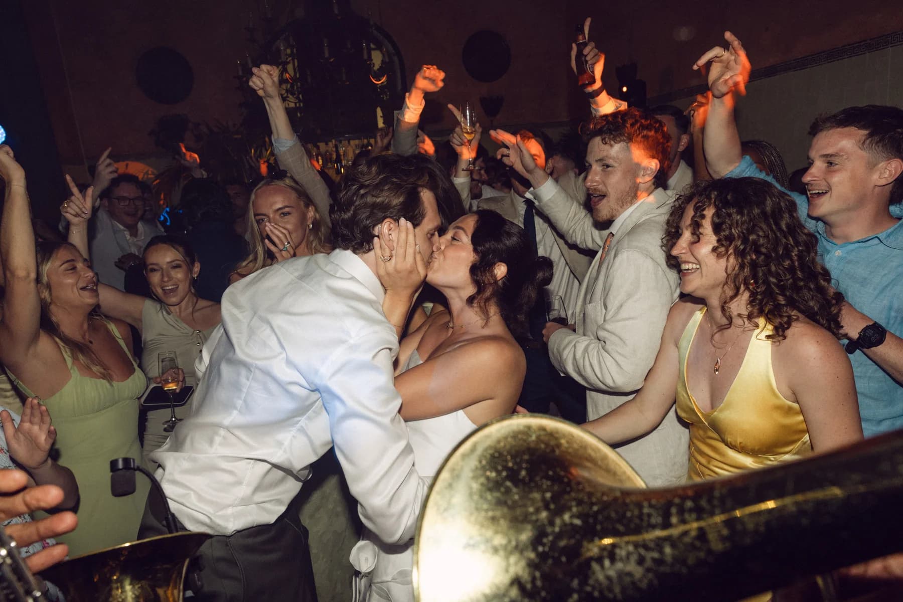 Newlyweds kissing among cheering guests on the dance floor