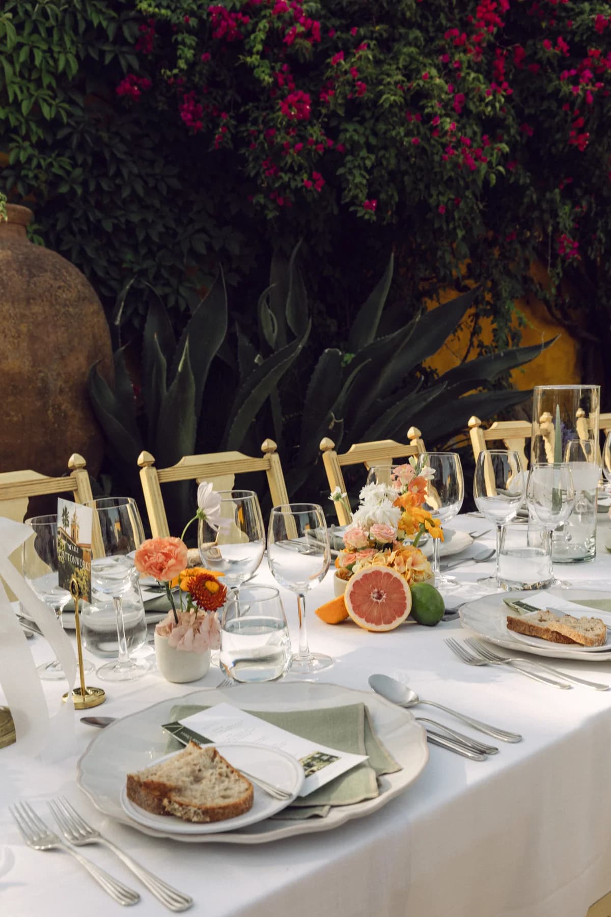 An outdoor reception table with fruit, flowers and candles