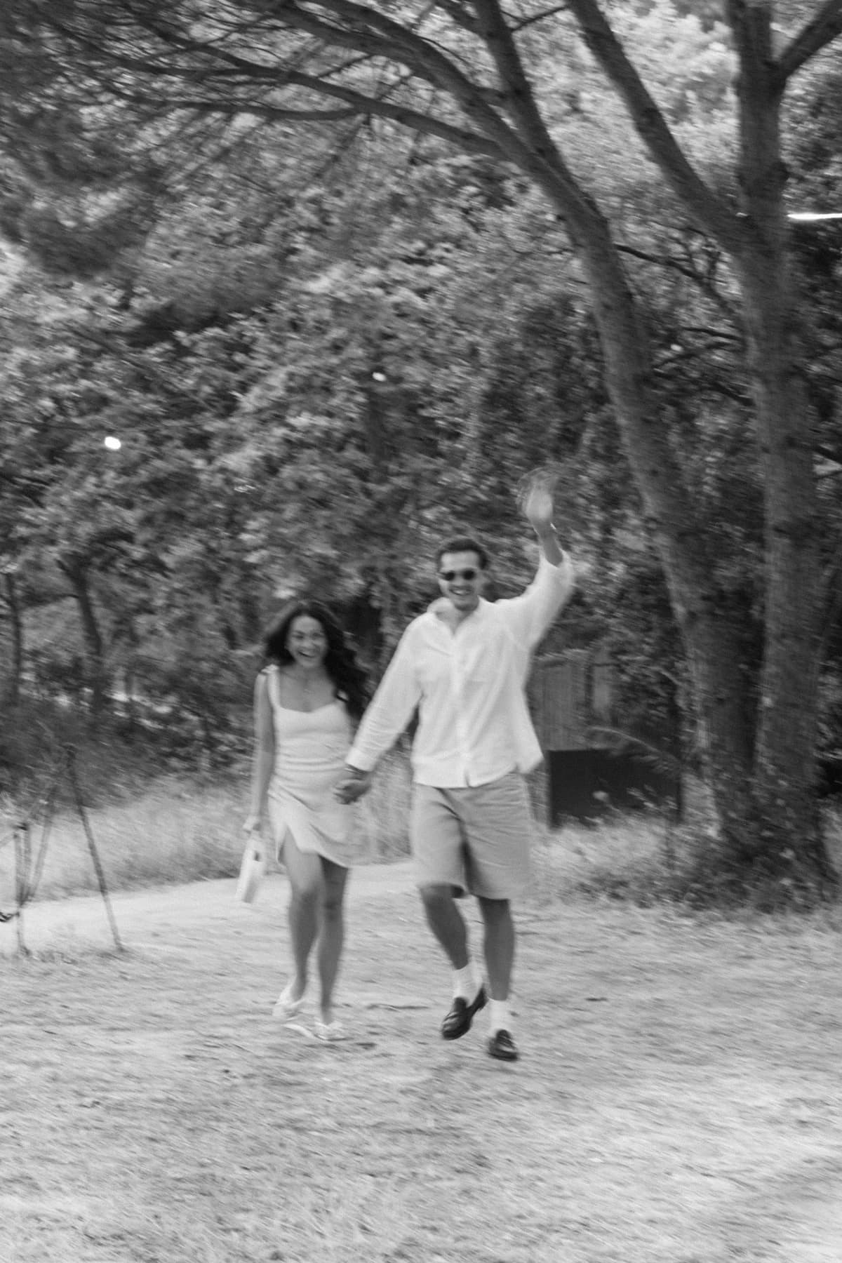 A couple walking together through the trees in black and white