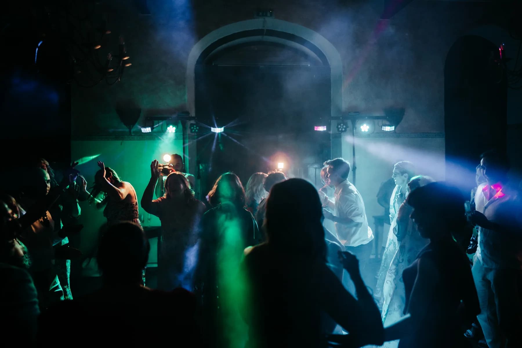 Wedding guests dancing beneath blue and green lights in the Olive Oil Press