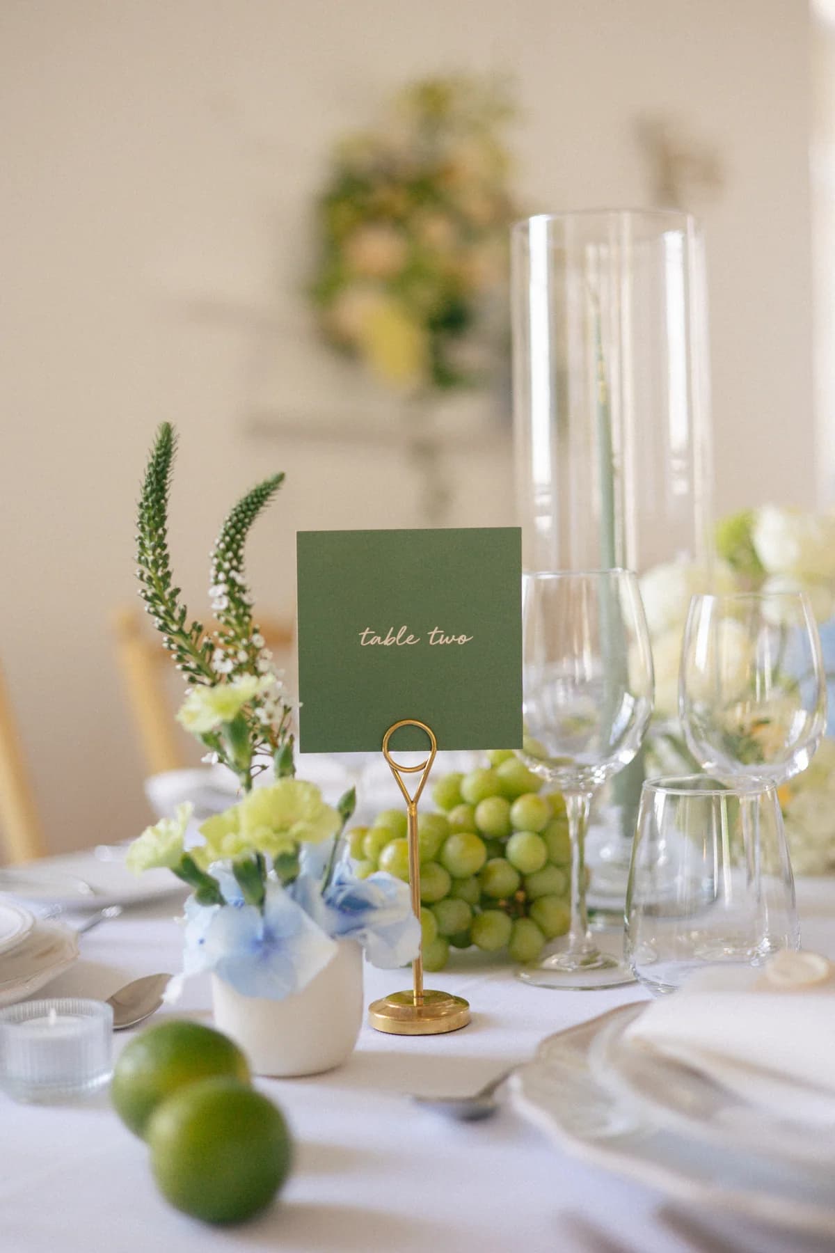 A green table card among grapes, flowers and glassware