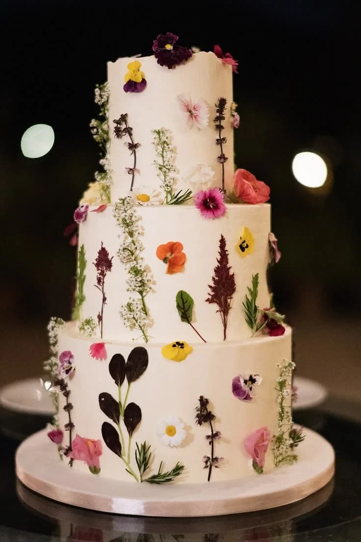 A tiered wedding cake decorated with pressed flowers