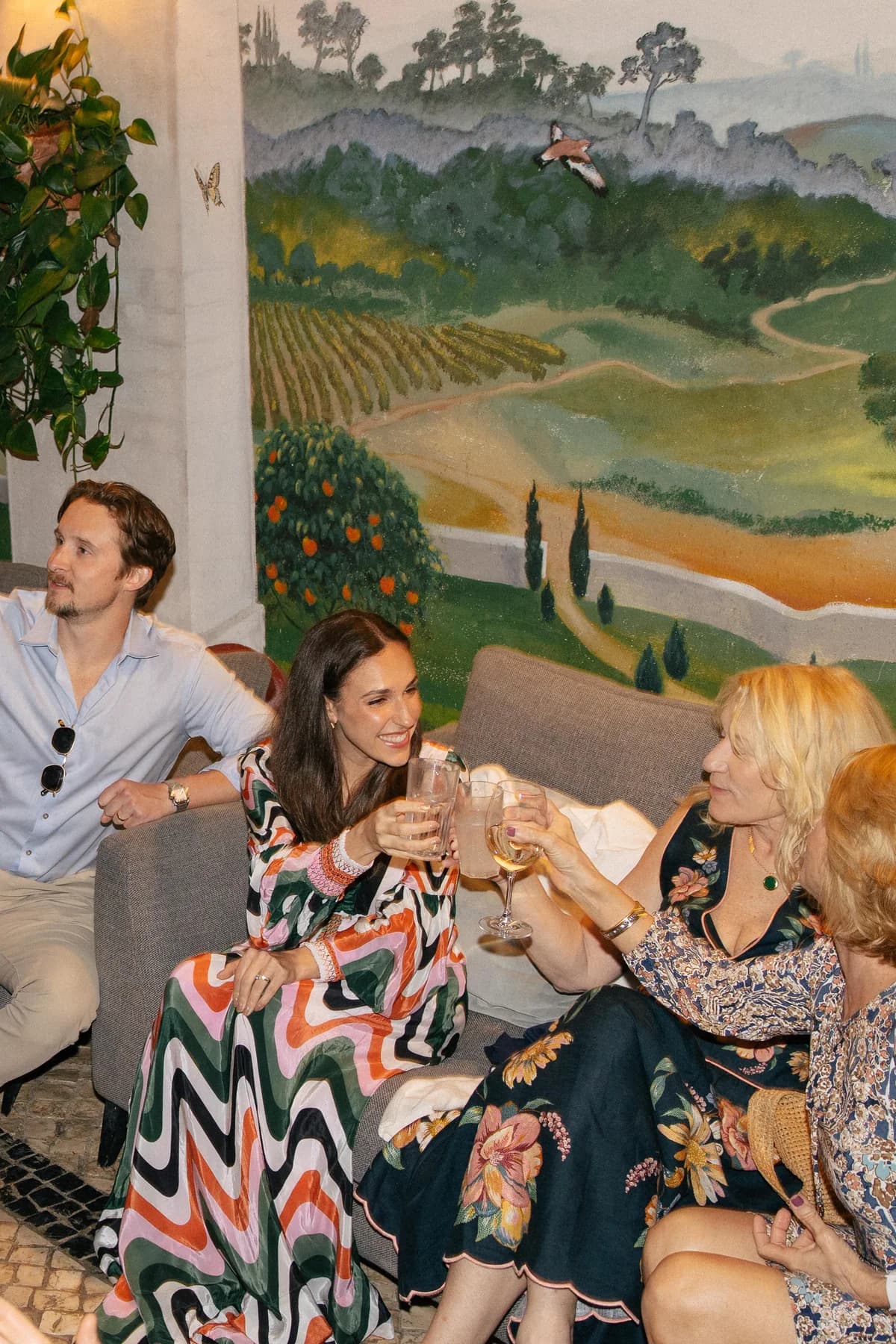 Guests chatting with drinks beside a painted mural