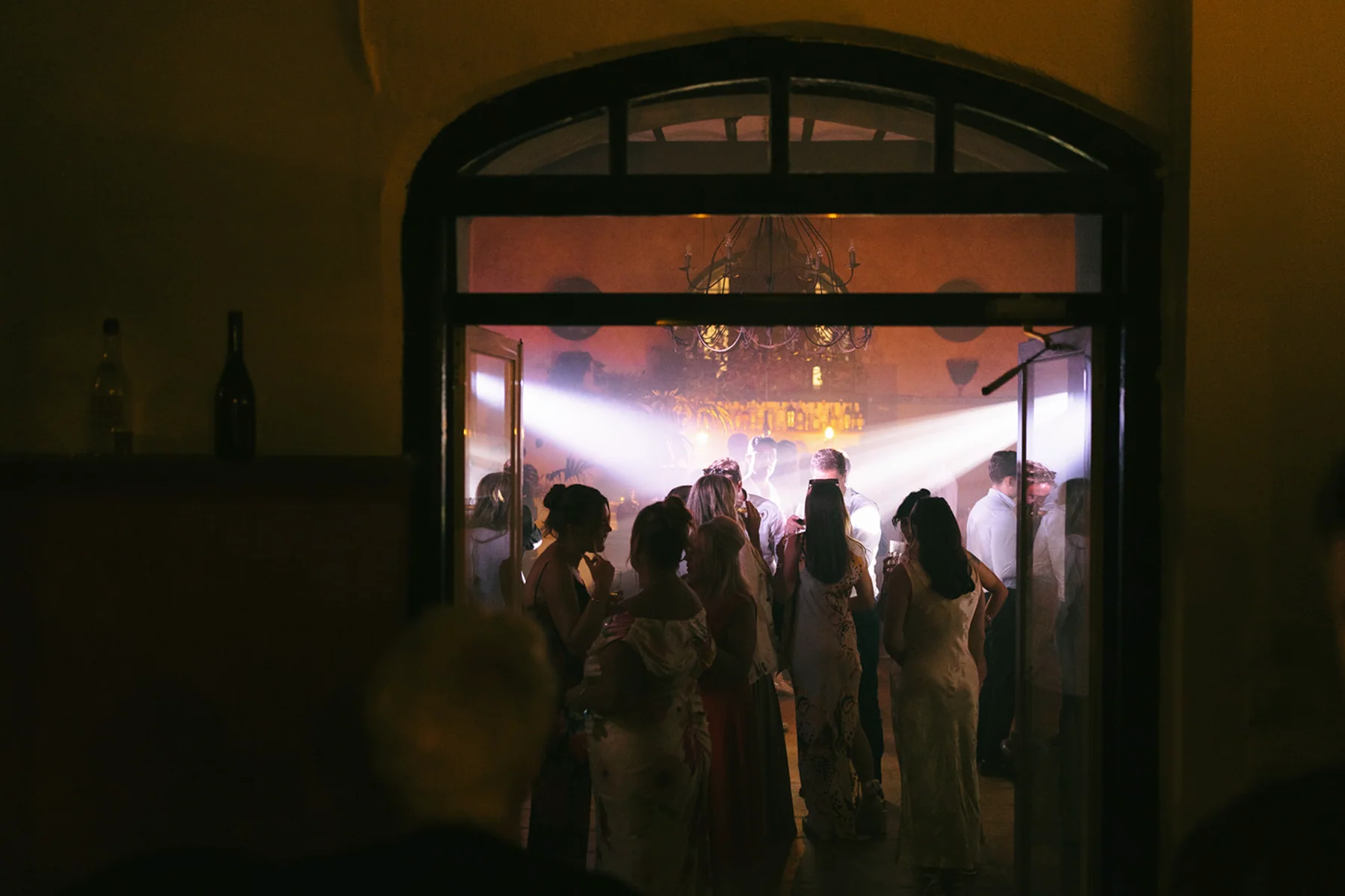 Guests dancing beneath party lights through an arched doorway