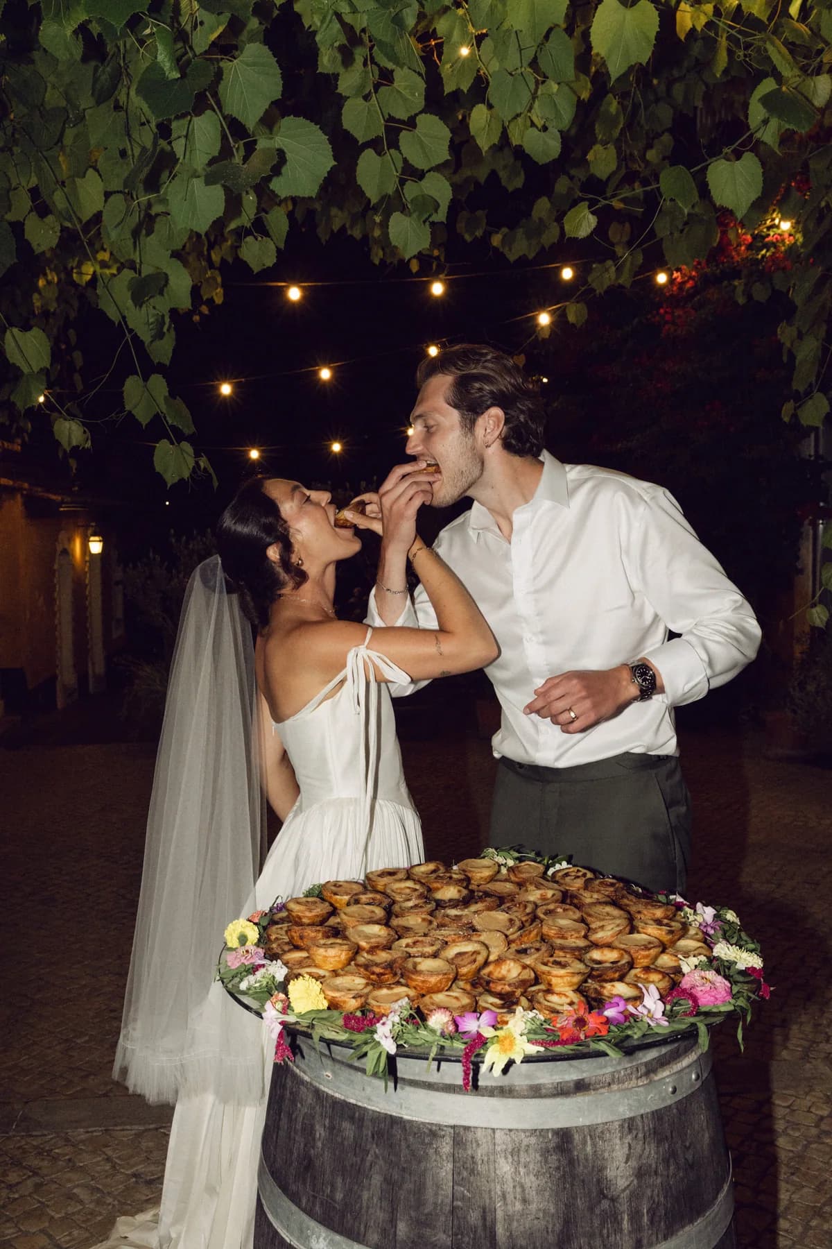 Newlyweds celebrating beside a dessert display on a barrel