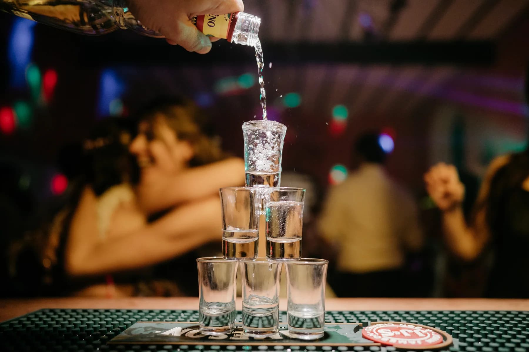 A drink being poured into a tower of shot glasses