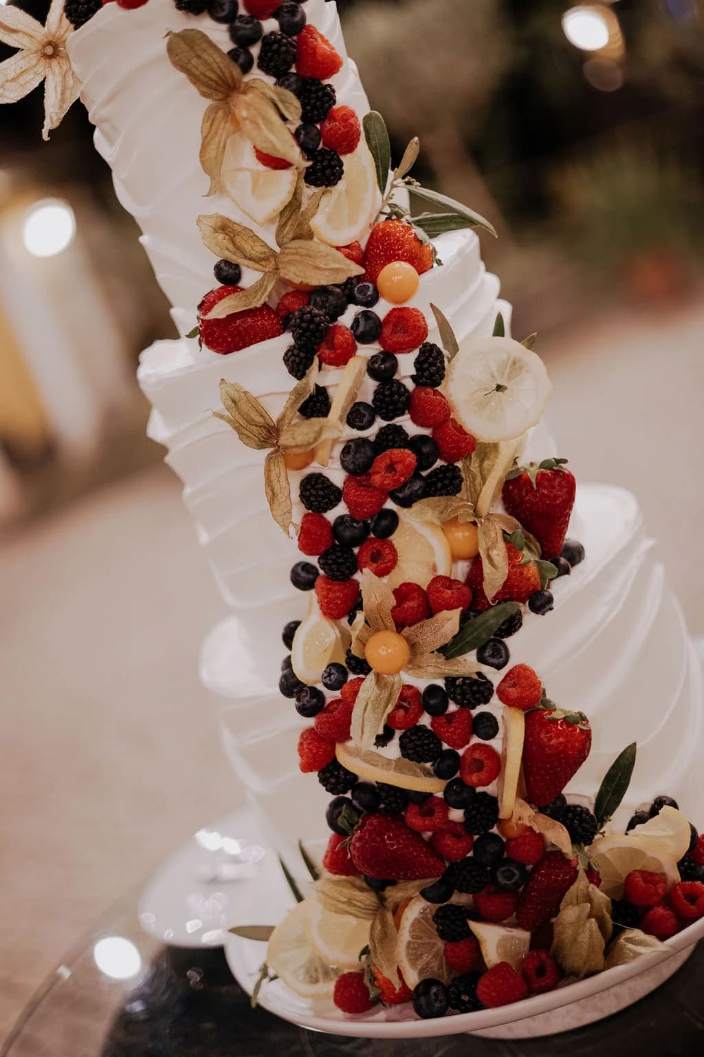 A tall wedding dessert decorated with berries and cream
