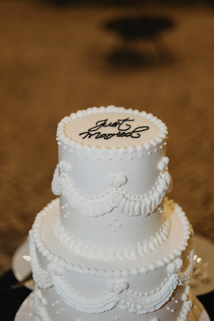 A tiered white wedding cake with piped icing
