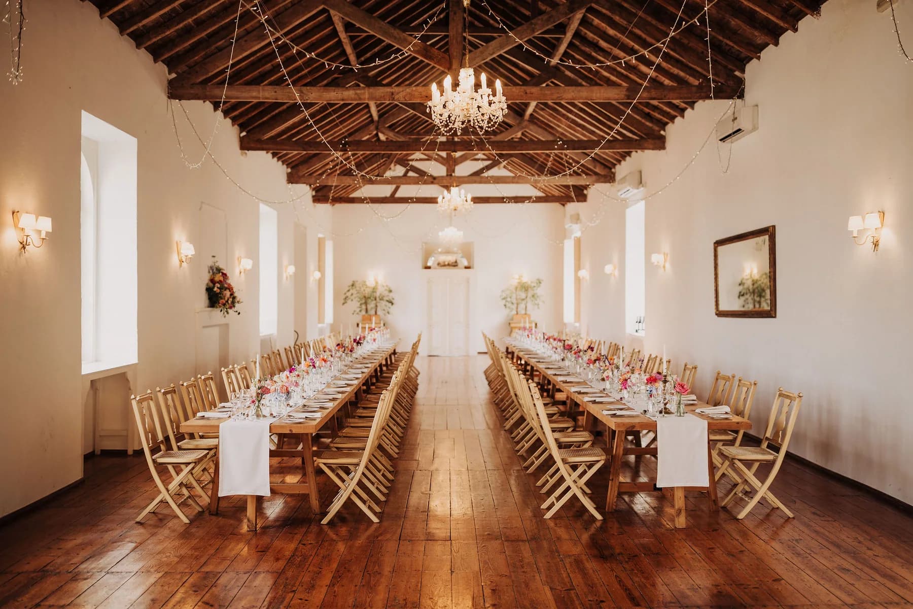 Long wedding tables beneath the dining hall's timber roof