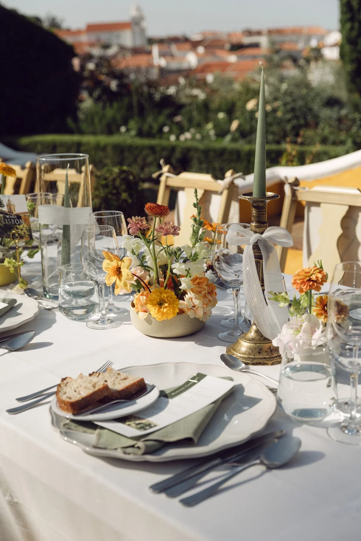 A sunlit outdoor place setting with flowers and candles