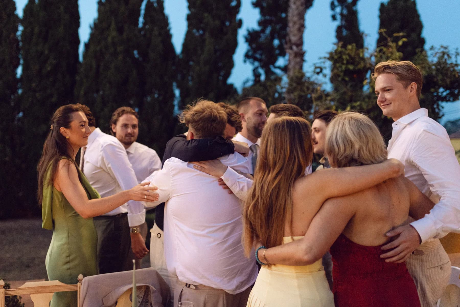 Wedding guests embracing beside the outdoor dinner tables