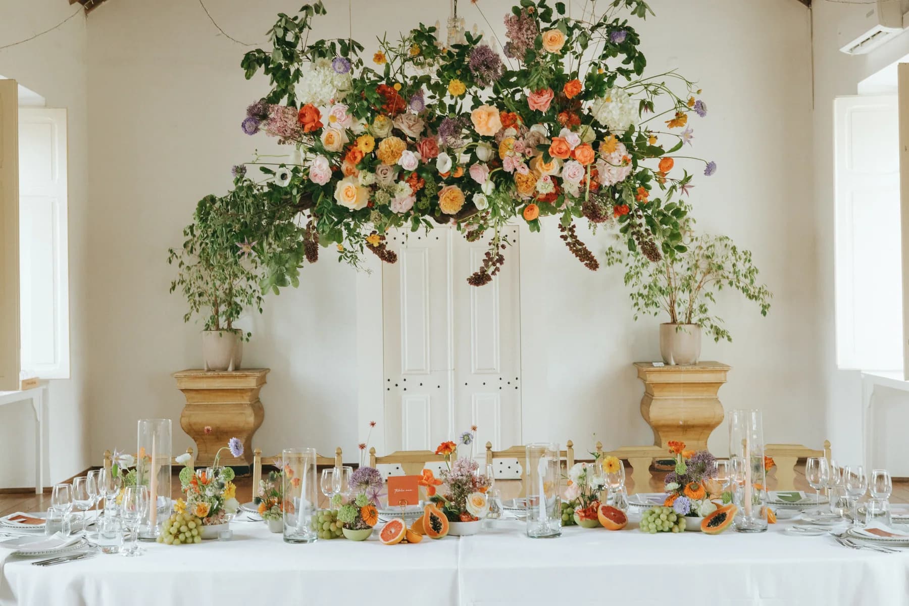 A hanging floral installation above a wedding dinner table