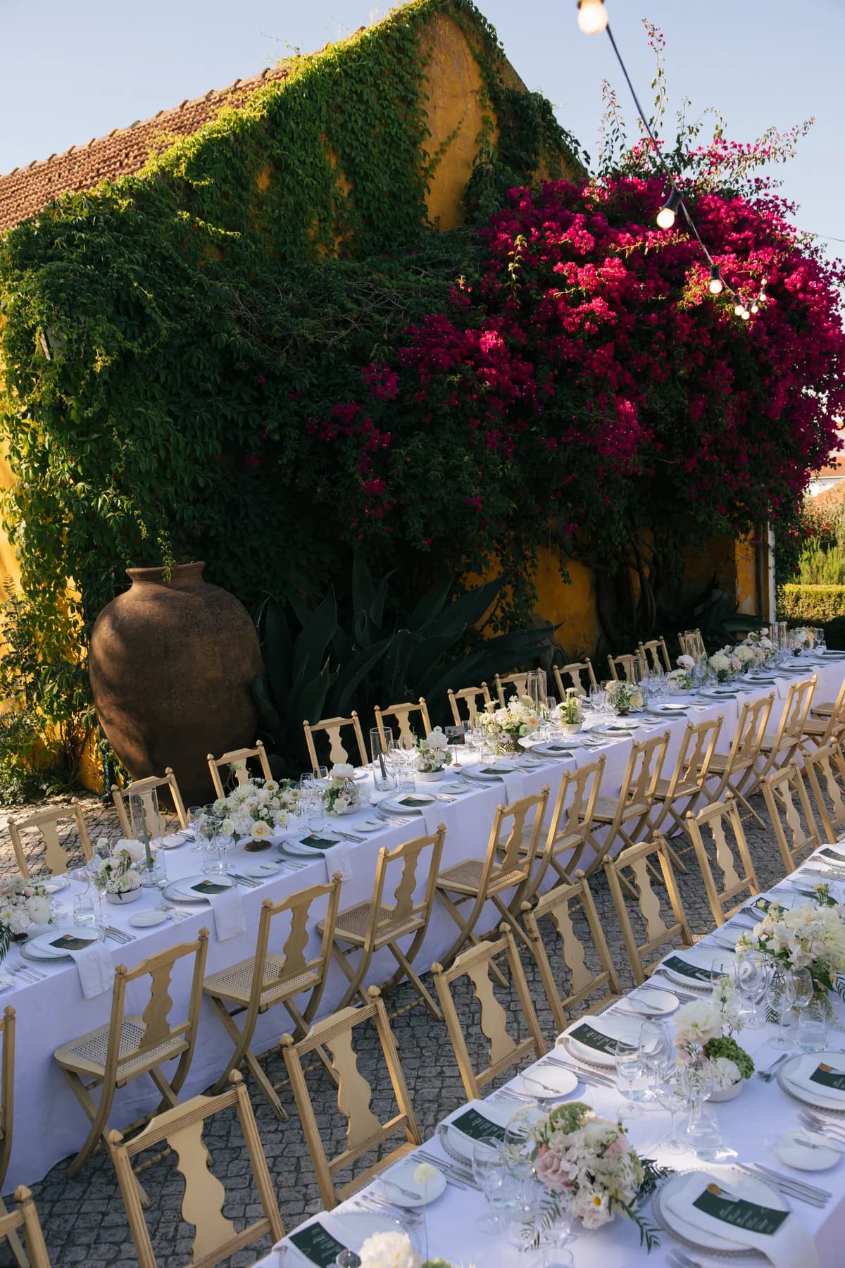Long reception tables beside a bougainvillea-covered wall