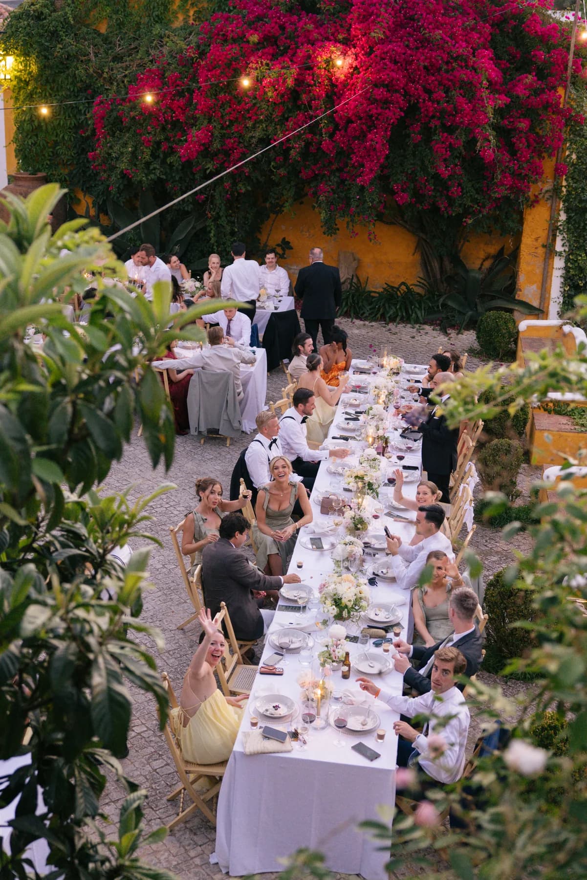 A long wedding table running beside flowering bougainvillea