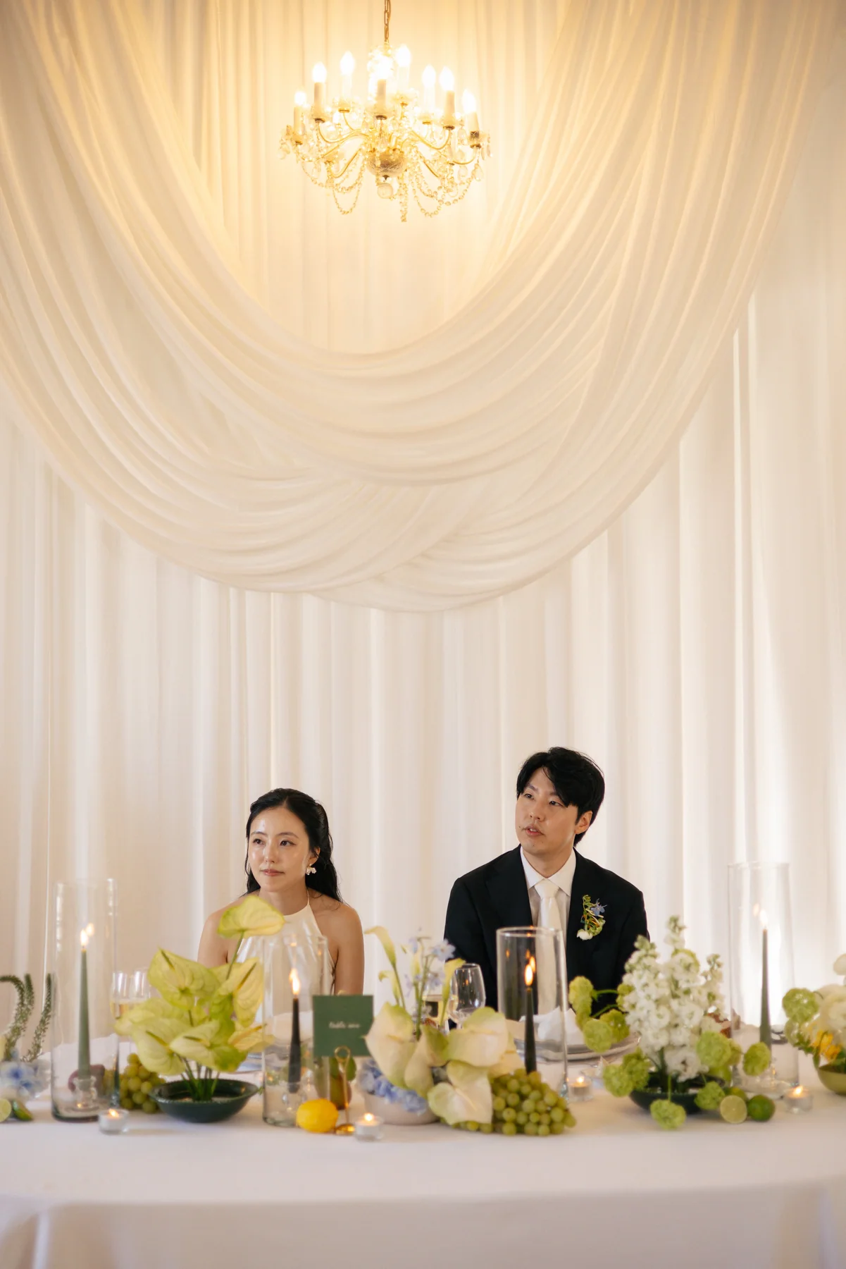 Newlyweds seated beneath soft white drapery