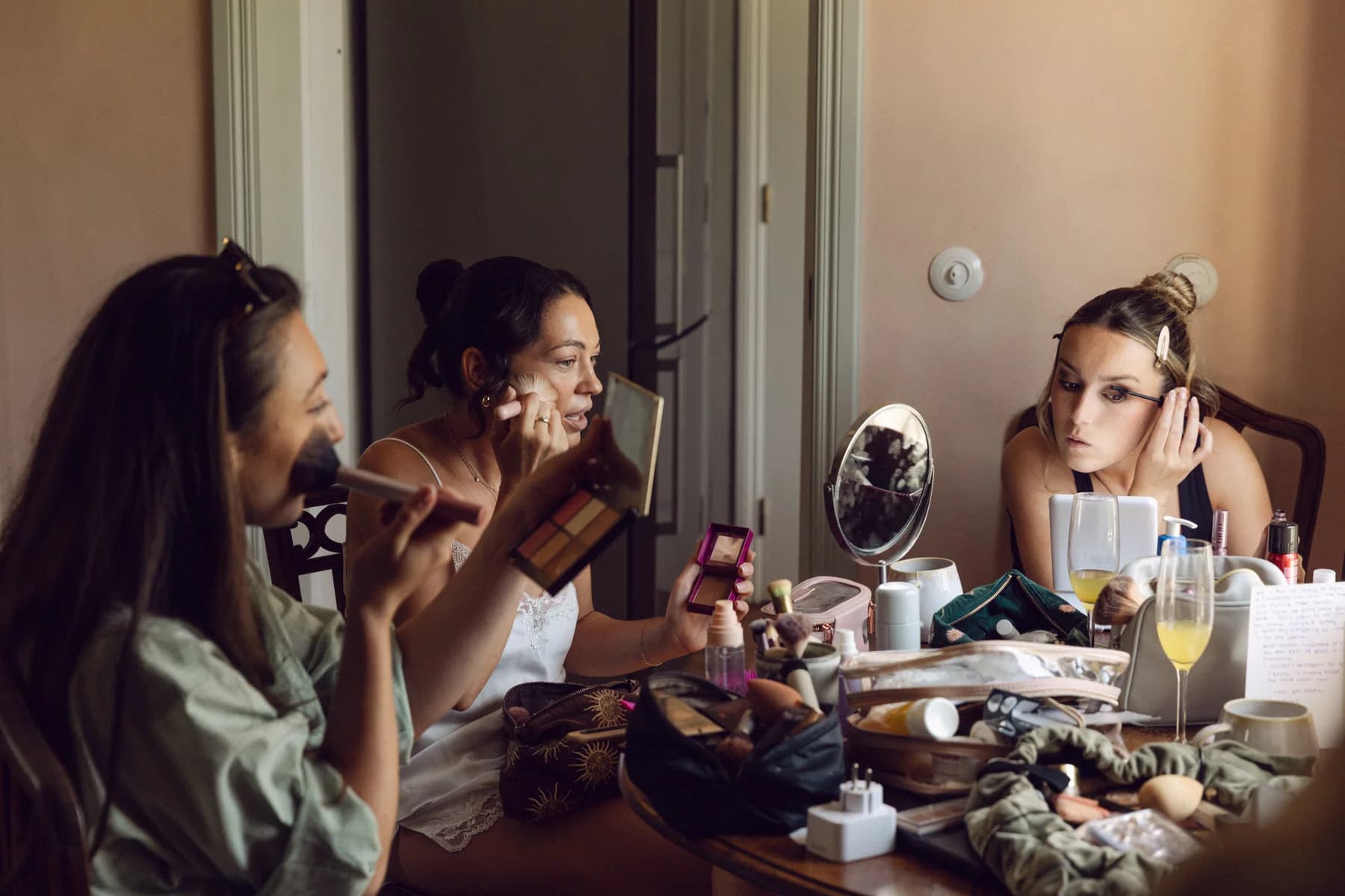Friends applying makeup around a table before the wedding