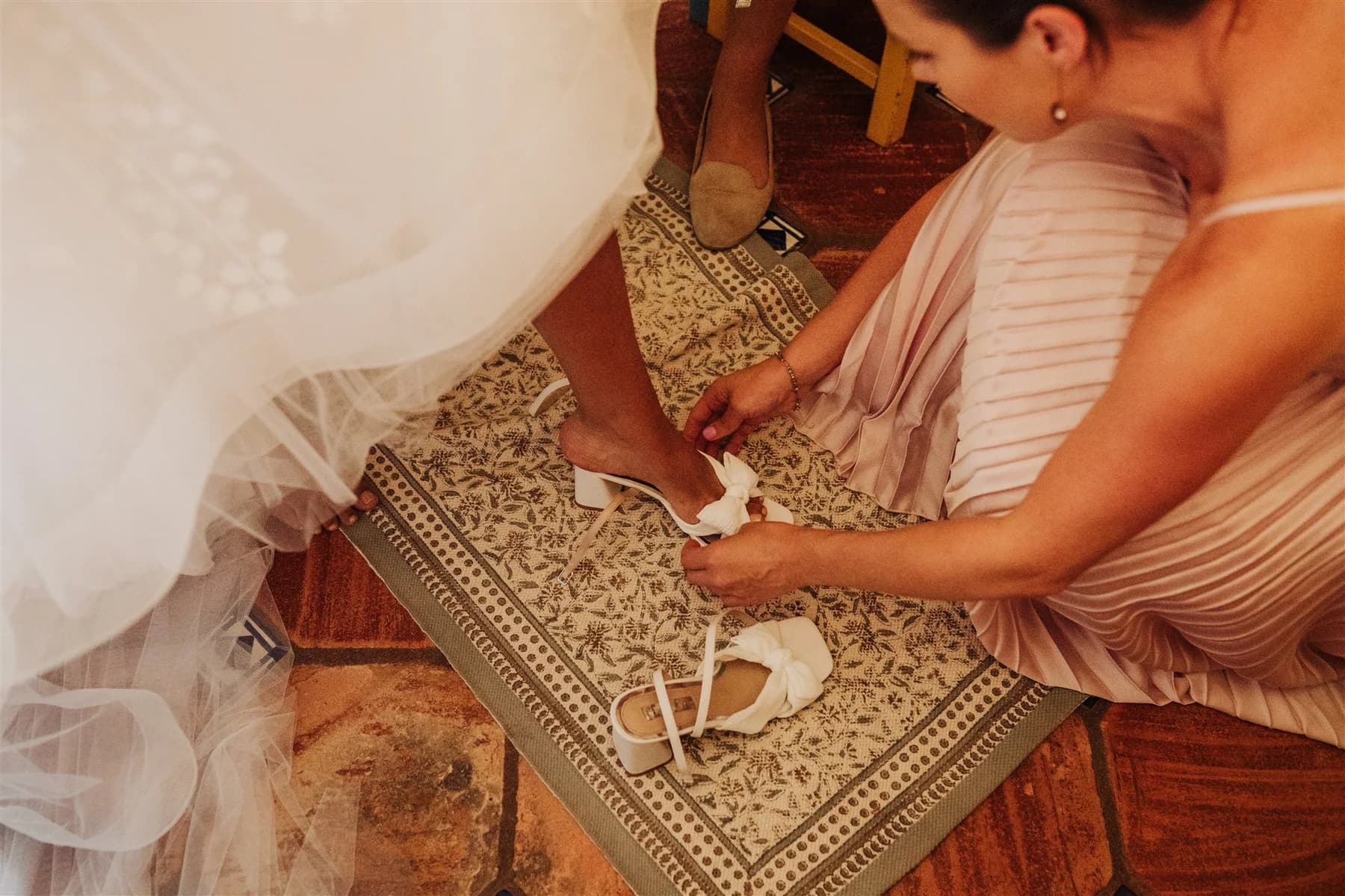A bridesmaid fastening the bride's wedding shoe