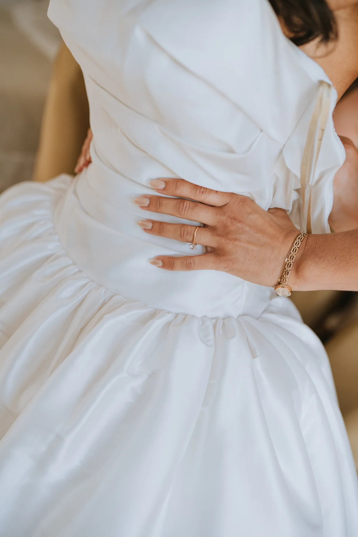 A close-up of a bride's dress and wedding ring