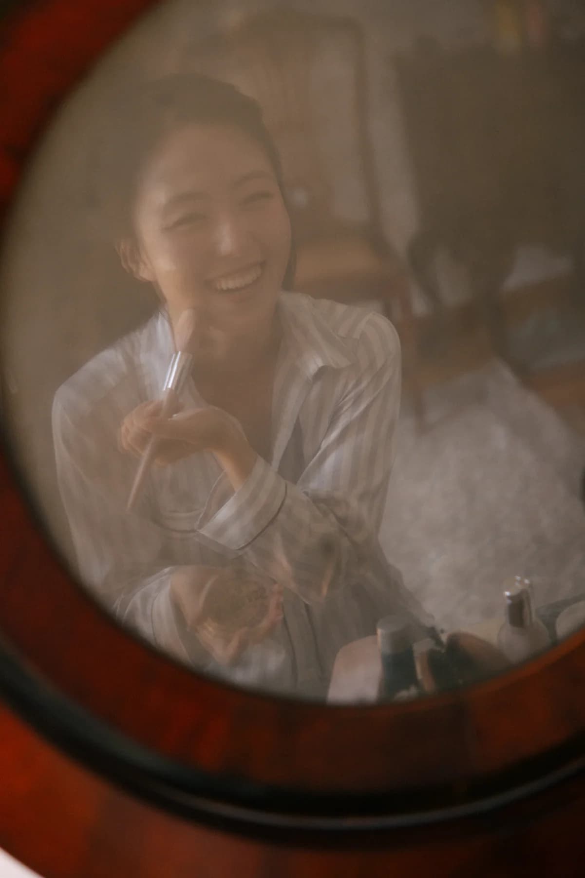 A bride smiling in the reflection of a dressing table mirror