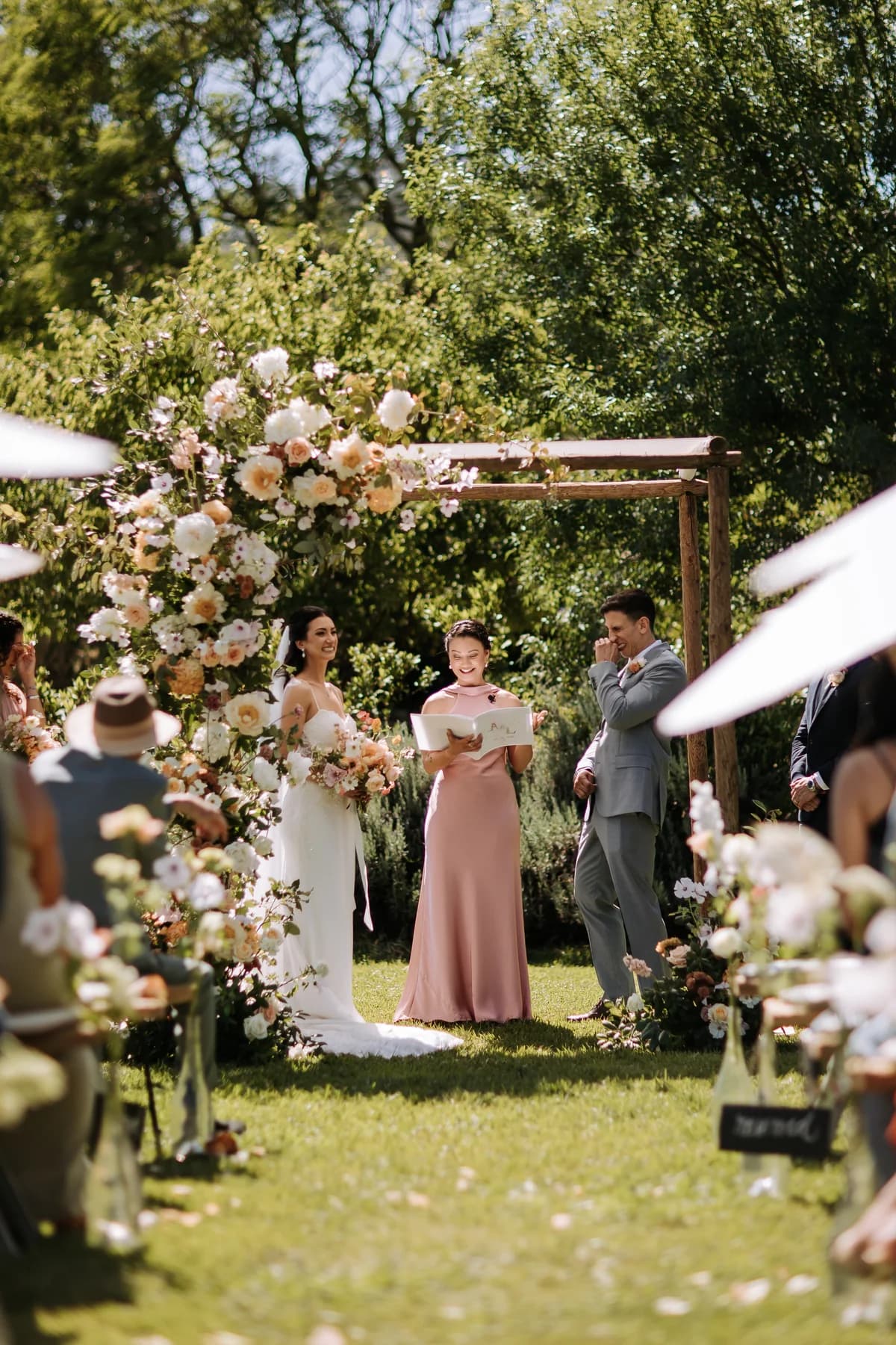 A wedding ceremony beneath a flower-covered arch