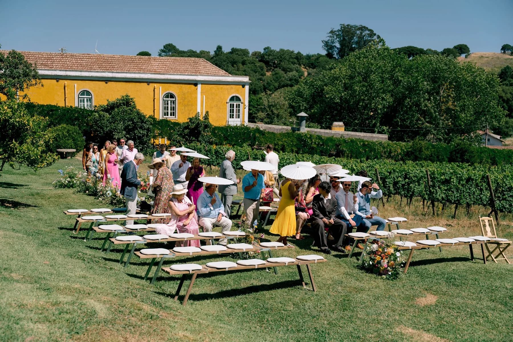 Guests seated for a garden ceremony beside the vineyards