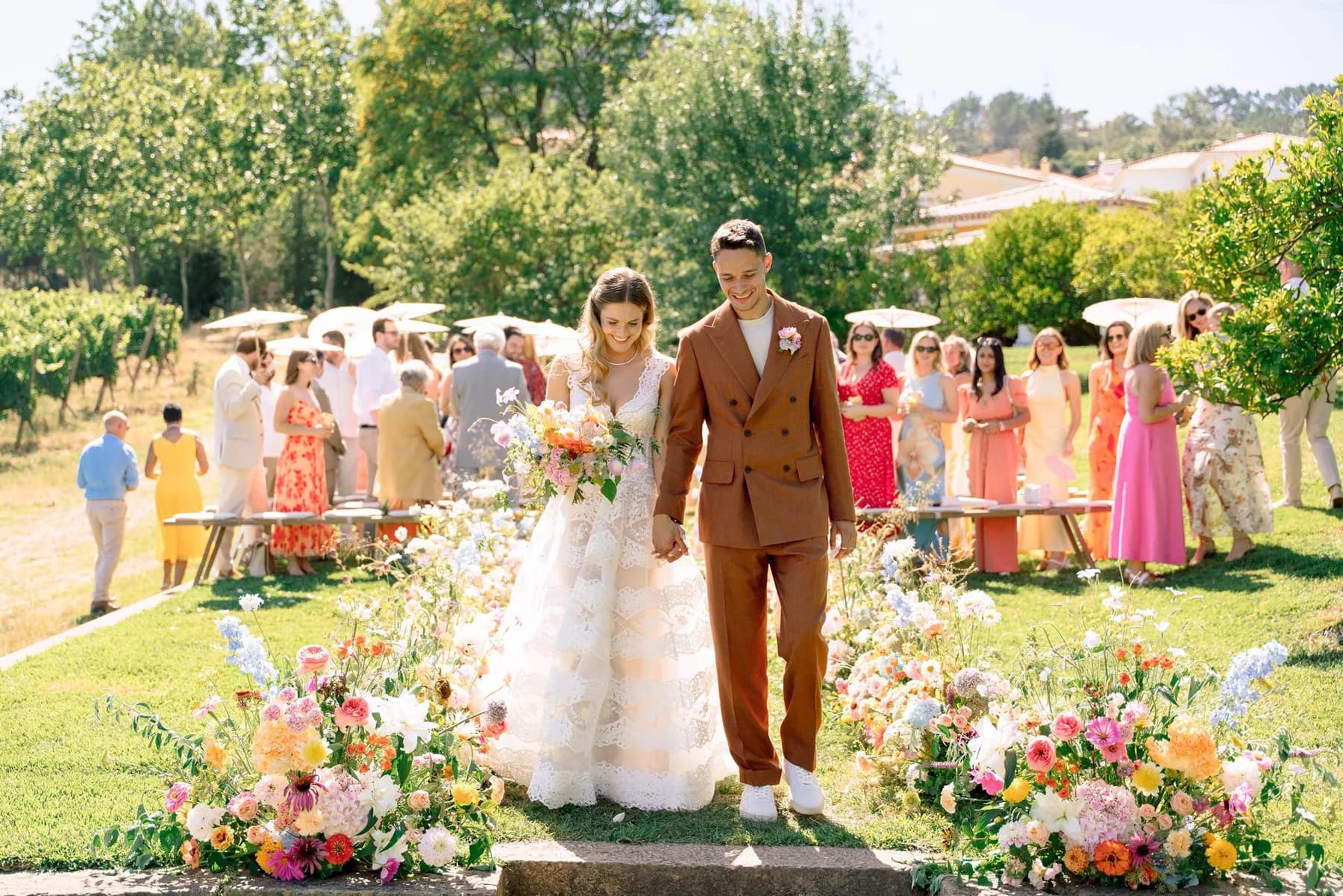 Newlyweds walking down a flower-lined garden aisle