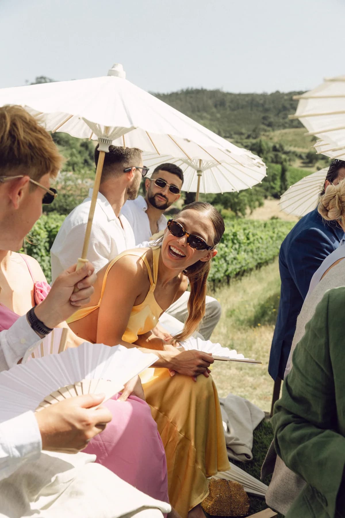 Guests smiling beneath parasols at an outdoor ceremony