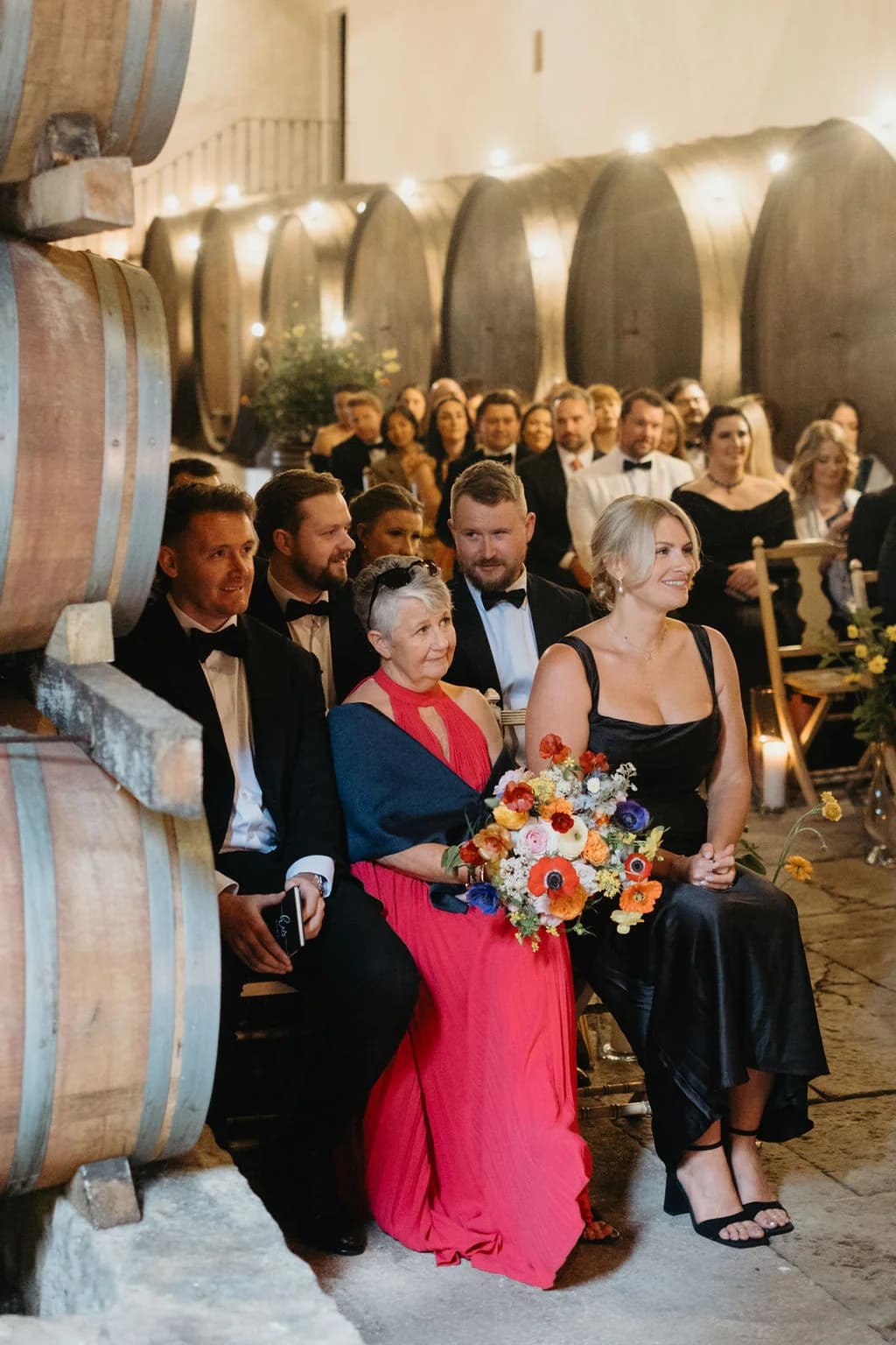 Guests attending a ceremony beside the Adega's wine barrels