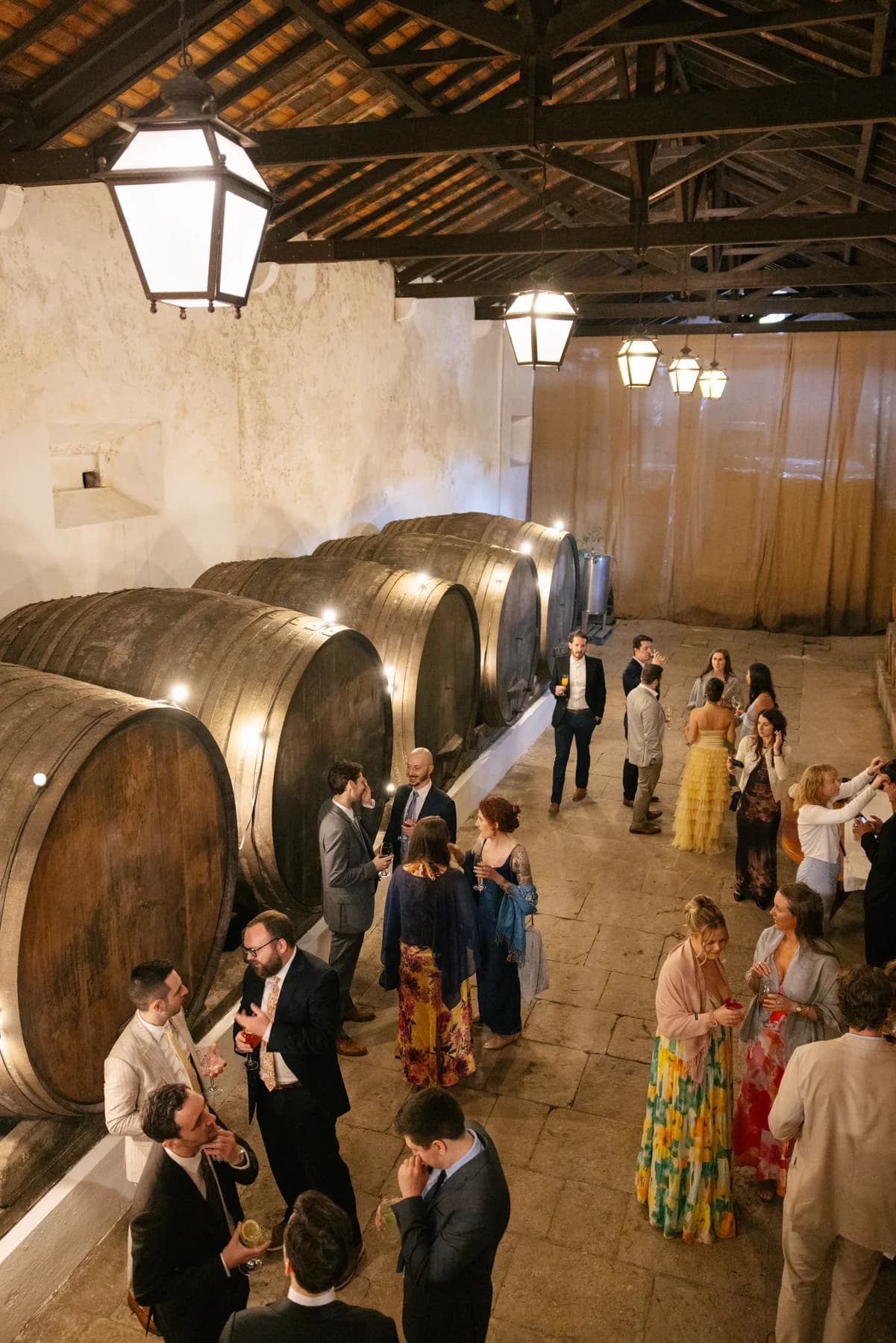 Guests enjoying drinks among the Adega's wine barrels