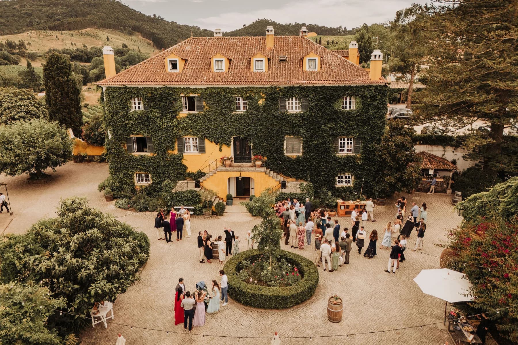An aerial view of guests enjoying drinks outside the main house