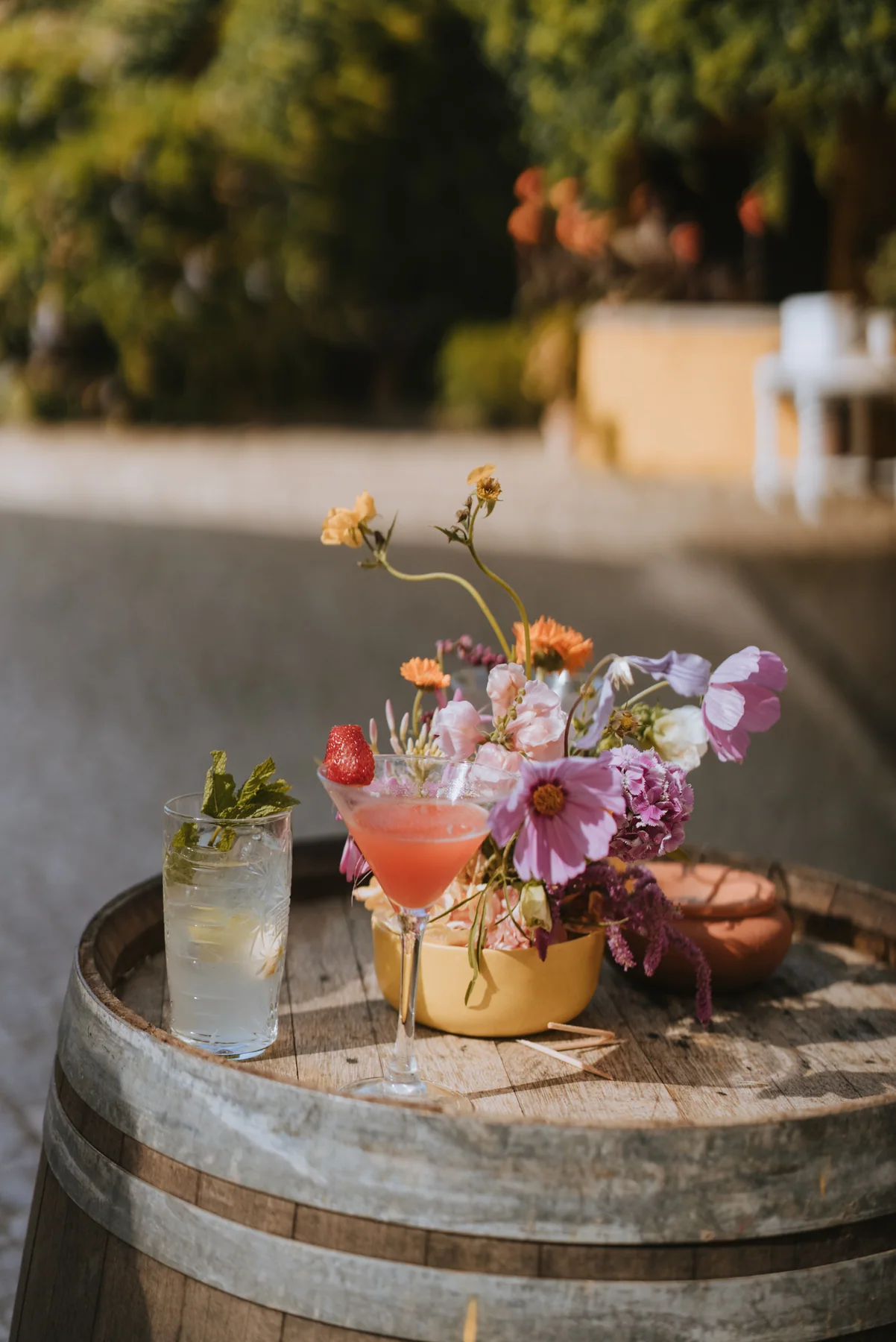 A small floral arrangement and drinks on a barrel table