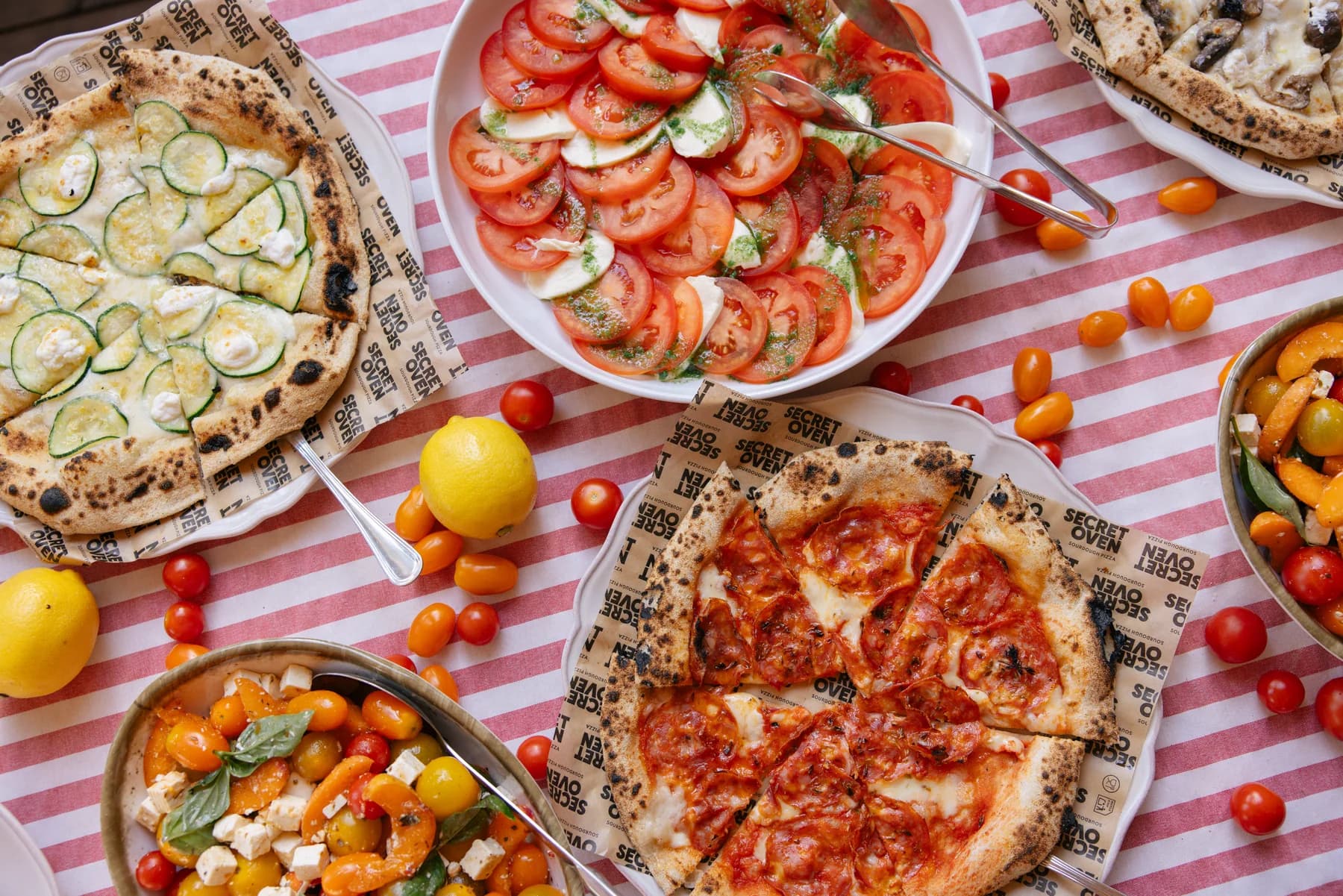 Pizza and tomato salads on a red and white checked tablecloth