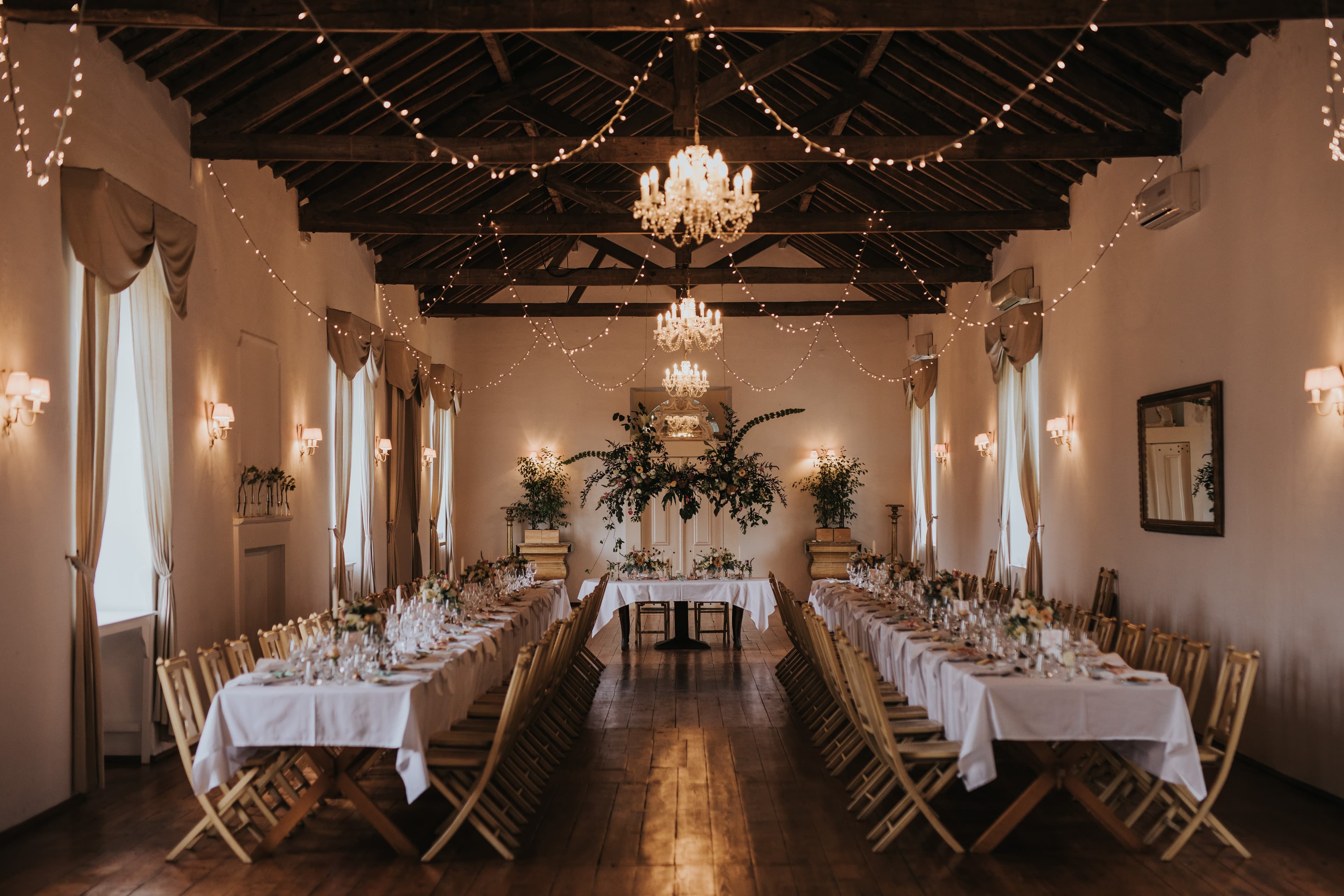 Tables set for a wedding dinner beneath the Great Hall's timber beams and chandeliers
