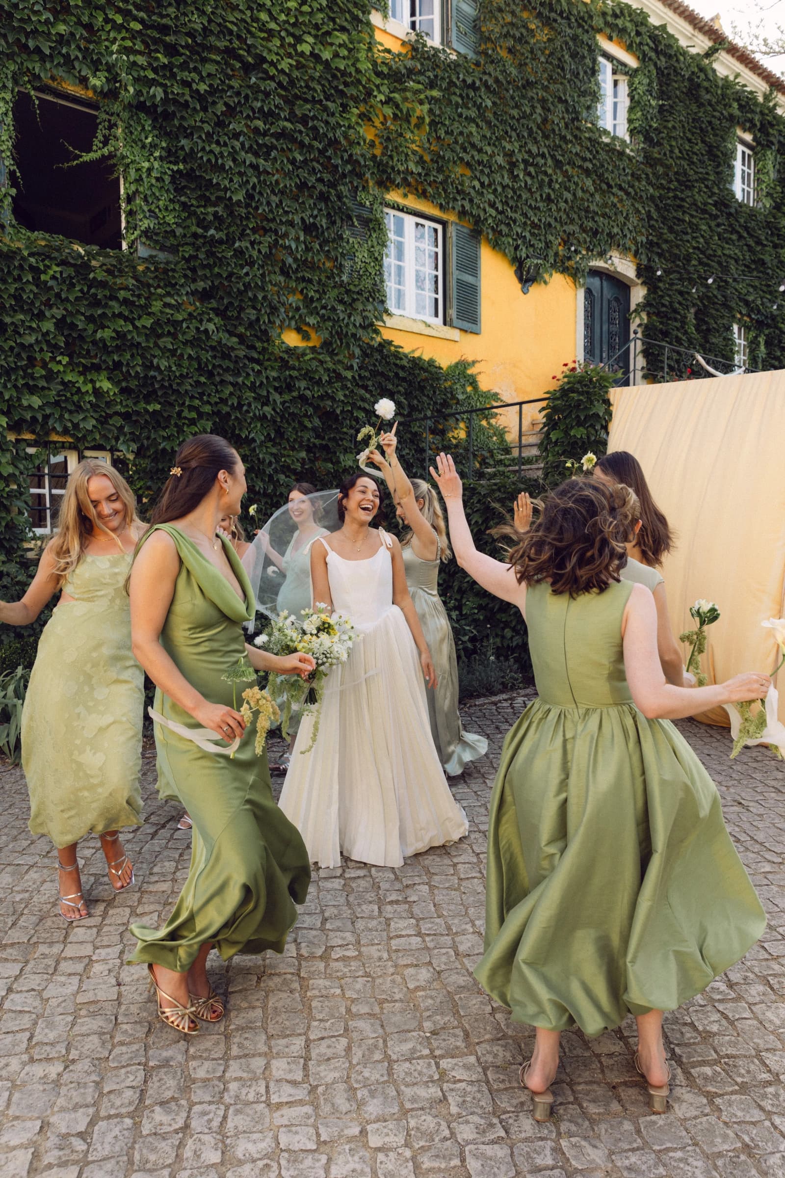 A bride and bridesmaids celebrating with drinks in the courtyard