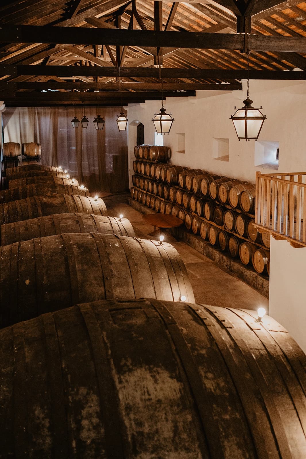Rows of wooden wine barrels beneath the Adega's exposed beams