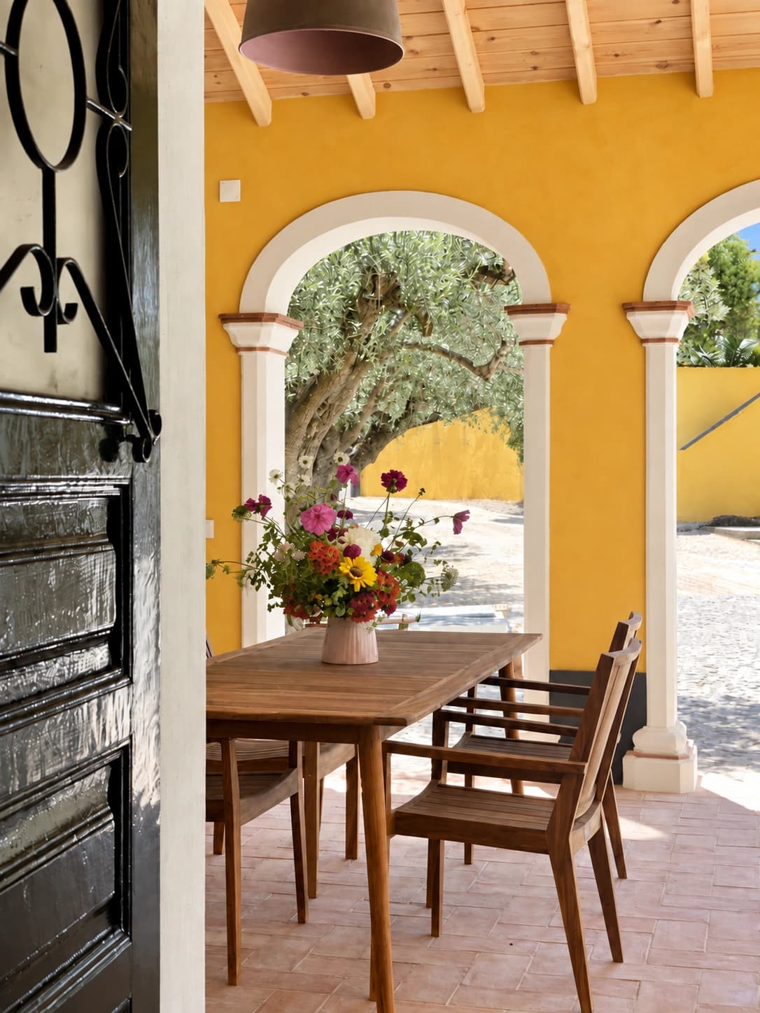 Dining table beneath the arches of Adega House's shaded veranda