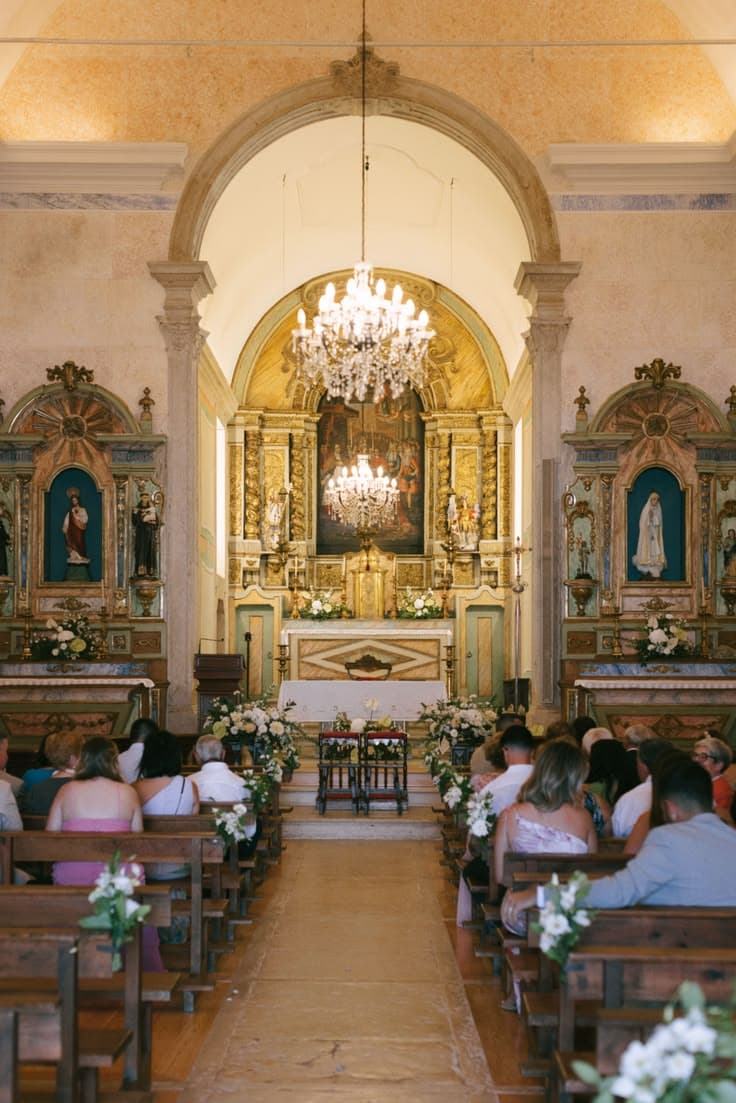 Church nave with chandelier, wooden pews, and golden altar