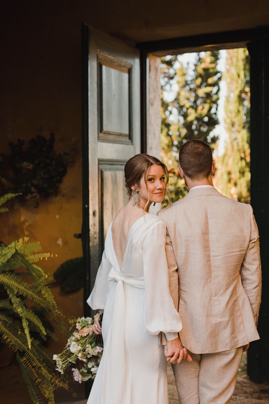 A newly married couple holding hands in the Quinta's open doorway