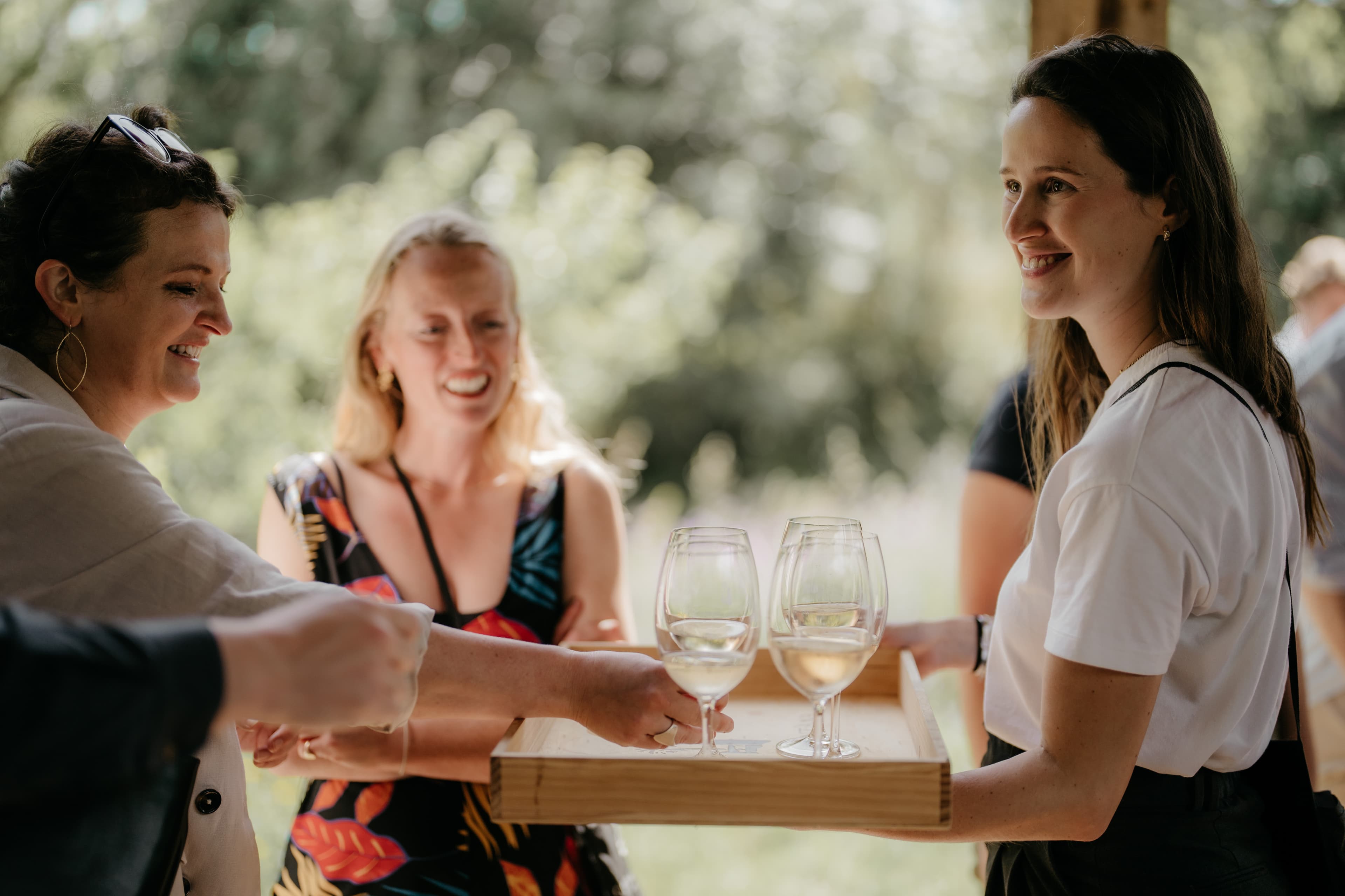 A member of the Quinta team serving white wine to guests in the garden